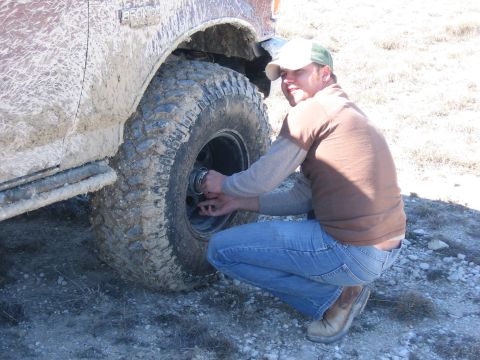 1996 Ford Bronco - Man changing a muddy tire on a 1996 Ford Bronco.