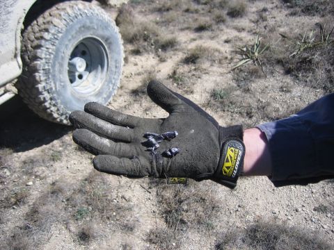 1996 Ford Bronco - Bullet fragments are held in a gloved hand, with a vehicle's tire visible in the background.