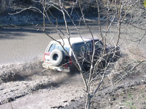 1996 Ford Bronco - This 1996 Ford Bronco is navigating a muddy terrain, creating a significant splash.