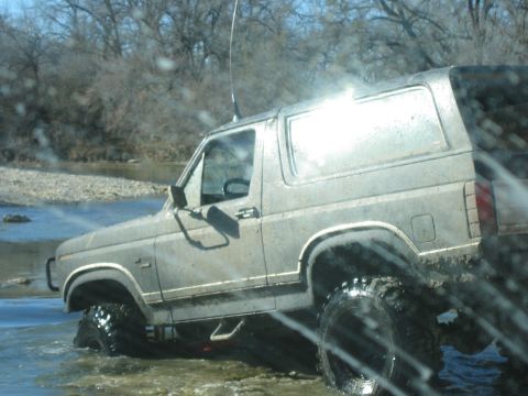 1996 Ford Bronco - This vintage Ford Bronco is navigating a rocky stream bed with large off-road tires.