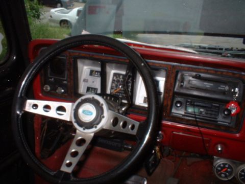 1979 Ford Bronco - The dashboard of a vintage truck features a wood-grain trim and an aftermarket steering wheel.