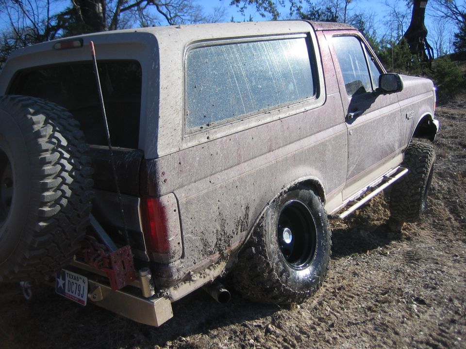 1996 Ford Bronco rear view, covered in mud, with spare tire mounted externally