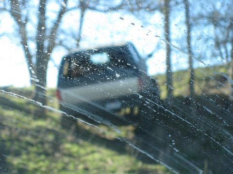 1996 Ford Bronco - A dark SUV is visible through a windshield covered in water spots and streaks.