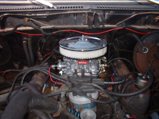 Engine bay with a chrome air filter and a red Edlebrock carburetor