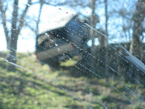 1996 Ford Bronco - A dark SUV is visible through a streaky, wet windshield on a sunny day.