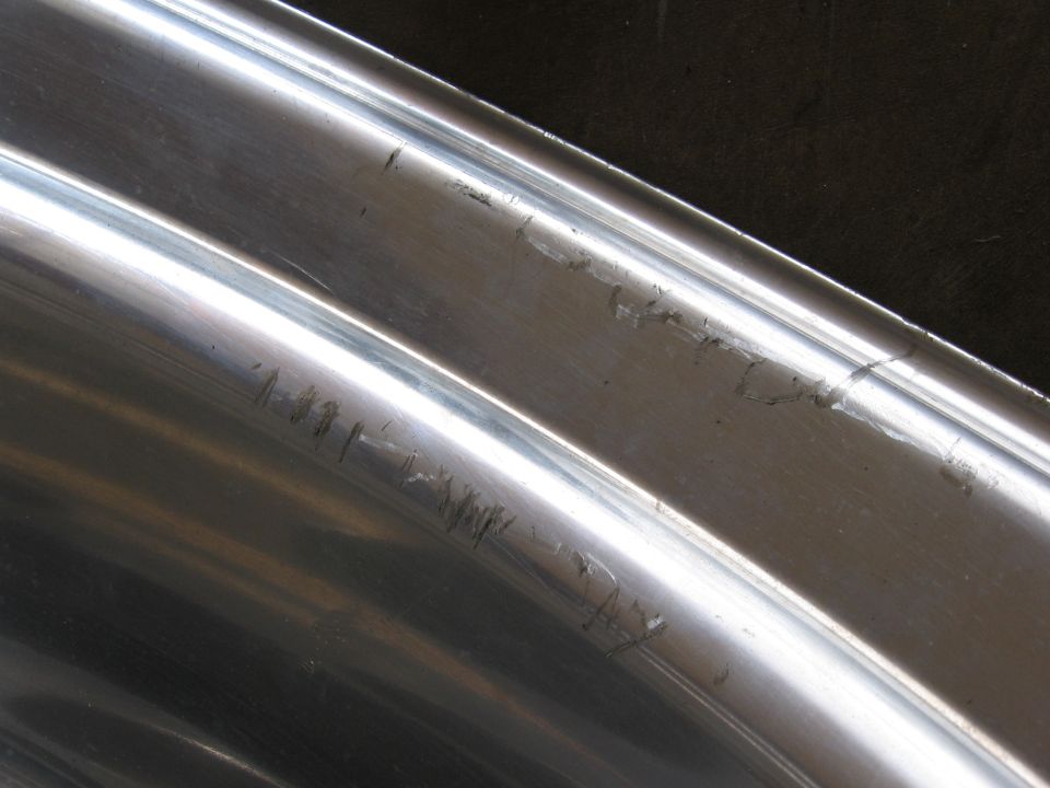 Close-up of two scratched chrome trim pieces, likely from a vehicle