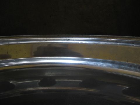 1974 Ford F-100 - Chrome wheel rim detail, showing wear and reflections on the metal surface.