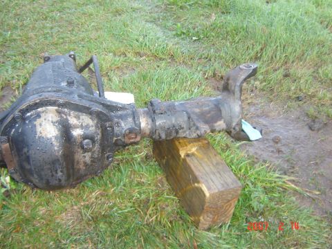 1993 Ford Bronco - A greasy differential axle assembly sits on grass, supported by a wooden block.