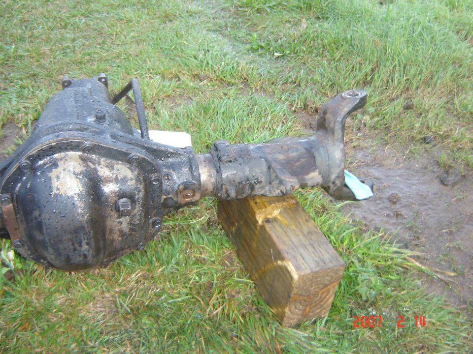 Differential axle assembly resting on a wooden block outdoors