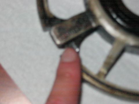 1991 Ford Bronco - A finger points to a bolt on a metallic wheel hub assembly, likely a vehicle part.
