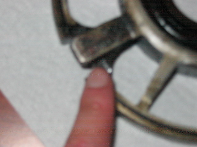close-up of a metal wheel hub with a finger pointing to a bolt