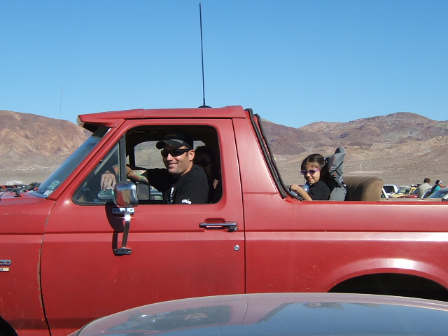 Red 1988 Ford Bronco with man driving and child in passenger seat