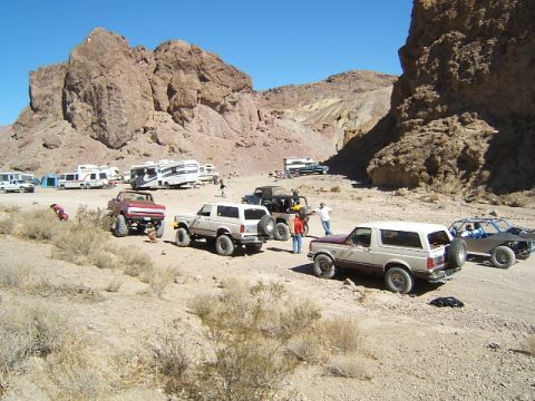 1988 Ford Bronco - Group of off-road vehicles and RVs gathered in a desert landscape.