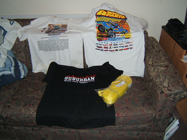 Three t-shirts and a yellow tow strap laid out on a couch