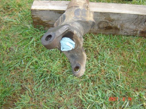 1993 Ford Bronco - A front axle knuckle, likely from a truck or SUV, is shown resting on grass with a blue rag stuffed into one of its openings.