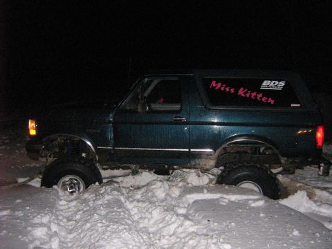 1995 Ford Bronco - A green Ford Bronco with a lifted suspension is stuck in deep snow at night.
