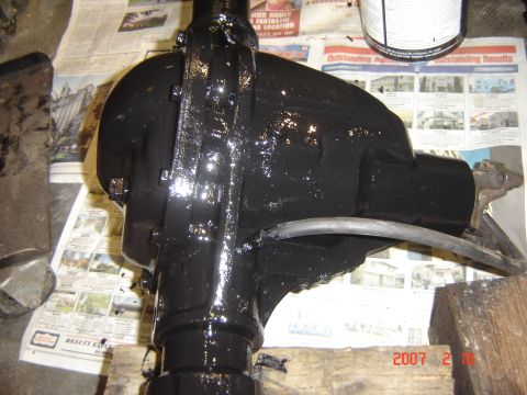 1993 Ford Bronco - Automotive differential housing freshly painted black sits on newspaper.
