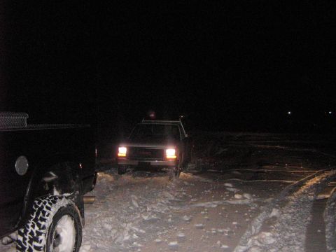 1995 Ford Bronco - Two SUVs are visible in a snowy landscape at night, with one vehicle's headlights illuminating the scene.