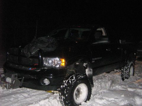 1995 Ford Bronco - A black pickup truck is stuck in the snow at night, equipped with a winch on the front bumper.