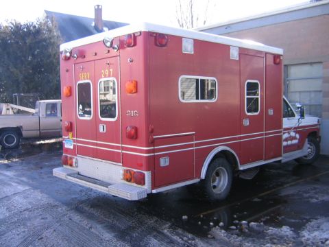 1984 Ford F-350 - Rear view of a red ambulance truck parked next to a pickup truck.
