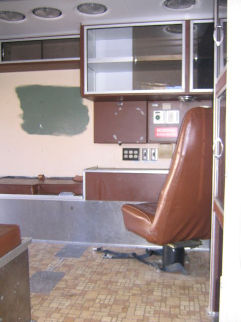 1984 Ford F-350 - The interior of a vehicle shows brown seats and cabinets, with a distinctive tiled floor and a patch of green paint on the wall.