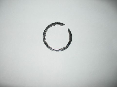 1991 Ford Bronco - A damaged metal ring lies on a plain white surface, showing a clear break in its circular form.