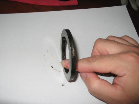 1991 Ford Bronco - A dark metal ring is held by a person's finger on a white surface.