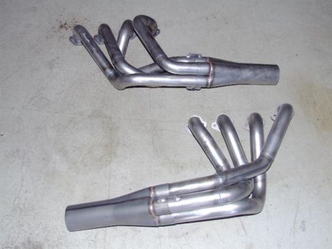 1990 Ford Mustang - Two sets of exhaust headers are shown on a concrete surface. One set is positioned above the other.