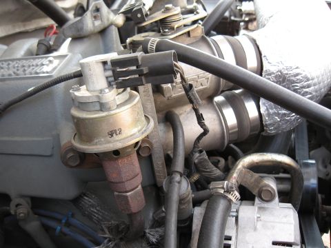 1994 Ford Bronco - Close-up view of engine parts, showing a sensor and various hoses and wiring.