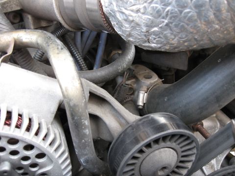 1994 Ford Bronco - Engine compartment detail showing various hoses, a belt tensioner pulley, and an alternator.