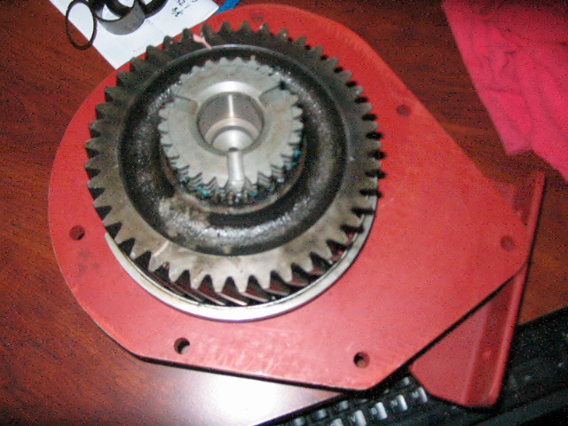 Red metal housing with two meshed gears, one larger than the other