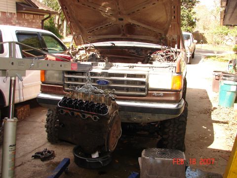 1987 Ford Bronco - A brown Ford truck, likely from the 1980s, is undergoing engine removal with the help of an engine hoist.