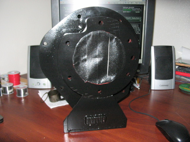 Black fan part with circular mounting holes and a central covered area