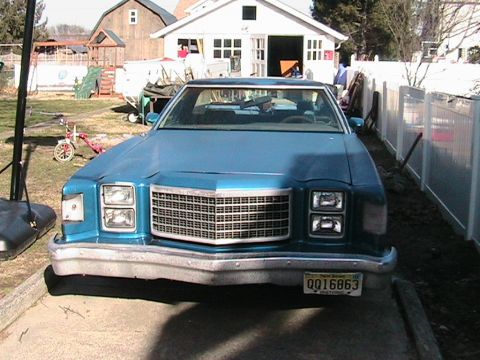 1973 Ford Ranchero - This blue Ford Ranchero, likely a 1977 model, is parked in a driveway with a house and barn in the background.