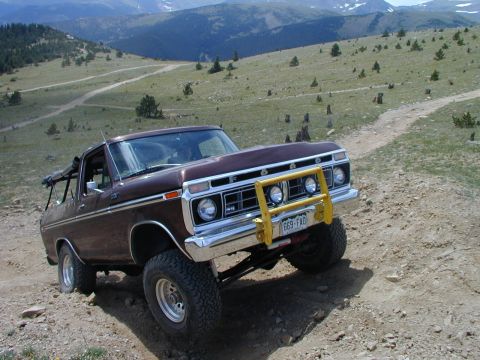 1979 Ford Bronco - This 1979 Ford Bronco navigates a mountain trail, its off-road capabilities with a prominent yellow bull bar.