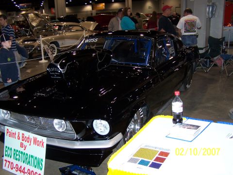 1979 Ford F-150 - Custom black car with a prominent hood scoop and roll cage displayed at a show.