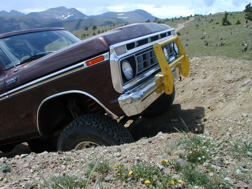 Maroon Ford Bronco with yellow grille guard crawling a rutted alpine trail
