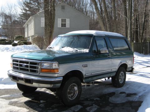 1994 Ford Bronco - Two-tone green and silver 1994 Ford Bronco in a snowy driveway.