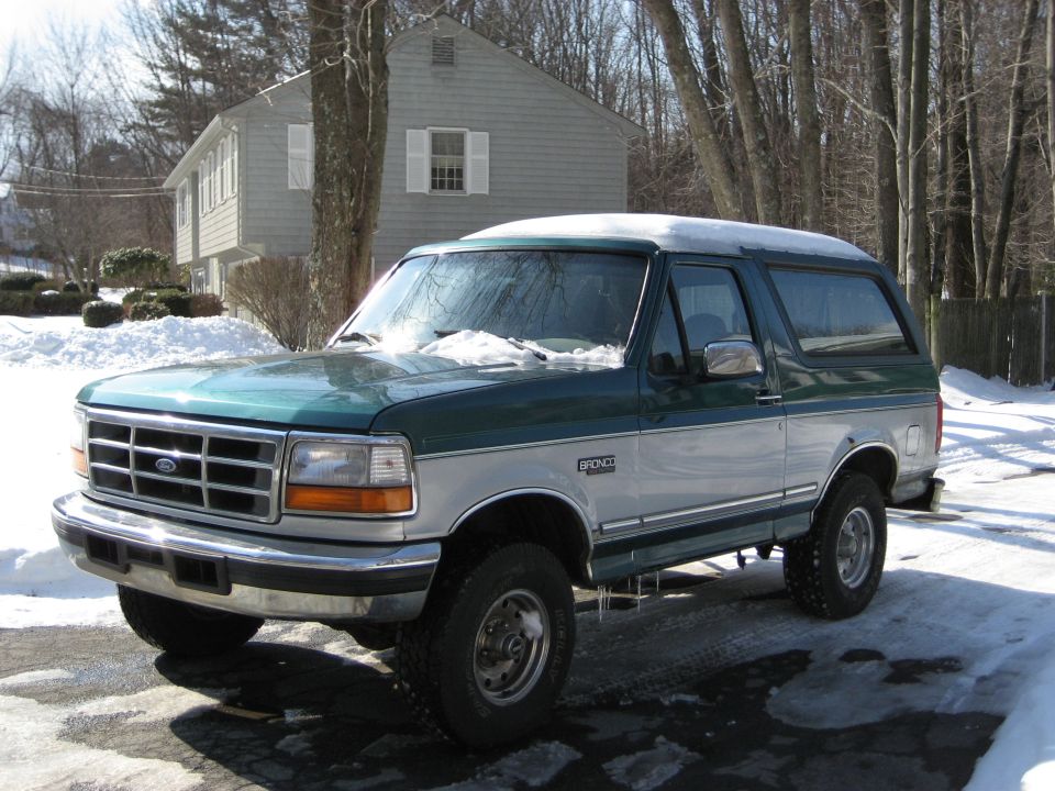 1994 Ford Bronco parked in snow, green and silver two-tone paint