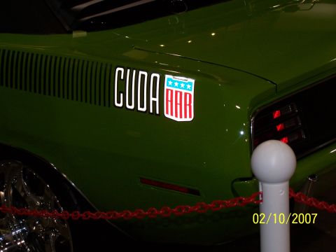 1979 Ford F-150 - Close-up of a green Plymouth Barracuda's rear quarter panel, showing the 'CUDA' and AAR decals.