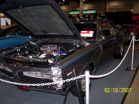 1979 Ford F-150 - A dark gray coupe with blue racing stripes is displayed with its hood open, showing the engine compartment.