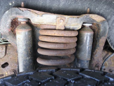1994 Ford Bronco - Front suspension components of a 1994 Ford Bronco, including a rusty coil spring and shock absorbers.