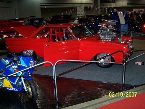 1979 Ford F-150 - Custom red coupe and blue Yamaha motorcycle on display at an indoor event.