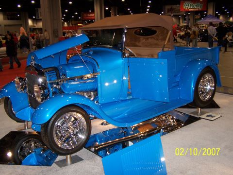 1979 Ford F-150 - A custom blue pickup truck is displayed indoors with its hood open, revealing the engine bay.