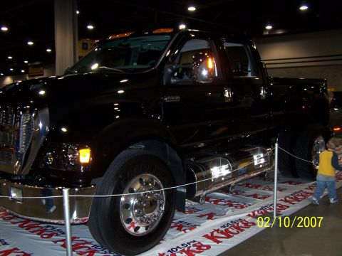 1979 Ford F-150 - A black truck is displayed indoors with a child observing it.