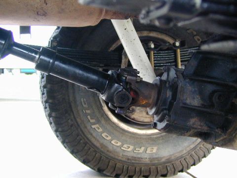 1979 Ford Bronco - Undercarriage view of a truck rear solid axle with leaf spring, driveshaft and U-joint above a BFGoodrich tire.