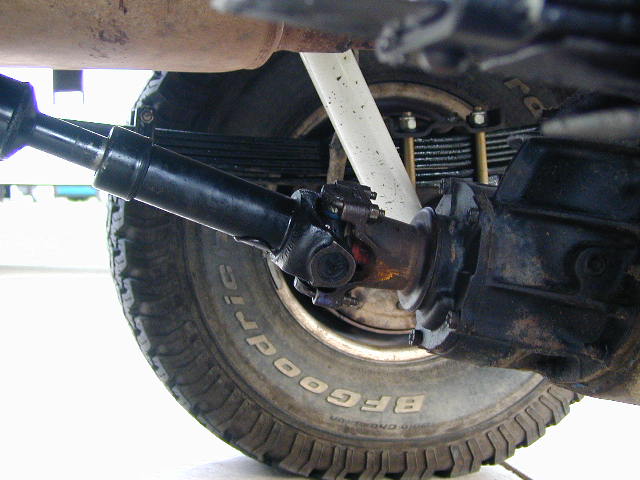 Underside view of rear leaf-spring solid axle, driveshaft U-joint and BFGoodrich tire