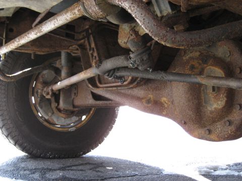 1994 Ford Bronco - Close-up view of the heavily rusted undercarriage, suspension, and differential of a vehicle.