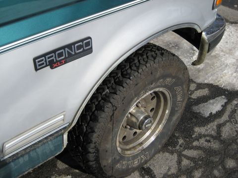 1994 Ford Bronco - Close-up of a 1994 Ford Bronco XLT's side panel and tire, showing its two-tone paint and fender badge.