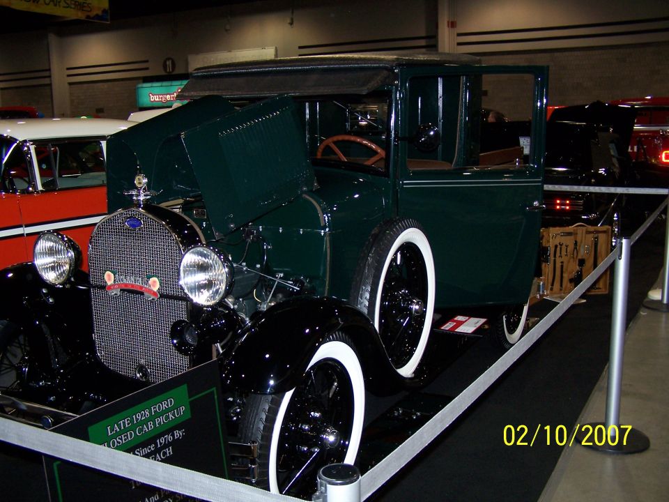 1928 Ford Model A closed cab pickup with hood open, white-wall tires, and a display of tools
